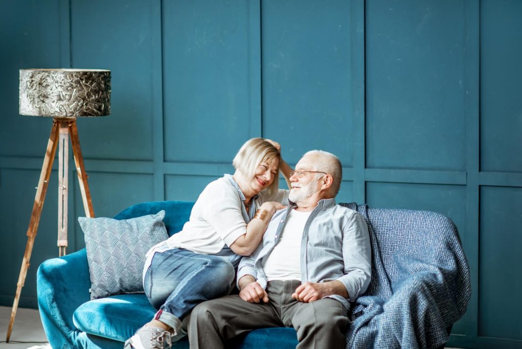 Reifes Paar sitzt gemütlich auf der Couch und lacht sich an